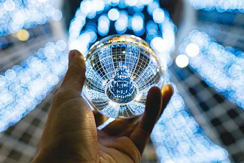 Hand holding a glass ball under a blue chandelier