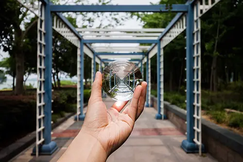 Hand holding a glass ball in a walkway