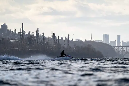 Person on a jetski with an industrial background behind them