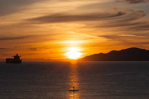 Paddleboarder in the shine of the sunset in the ocean 