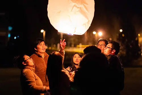 People crowd around a lit Chinese lantern