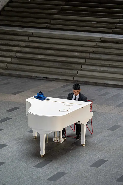 Person playing piano beside concrete stairs