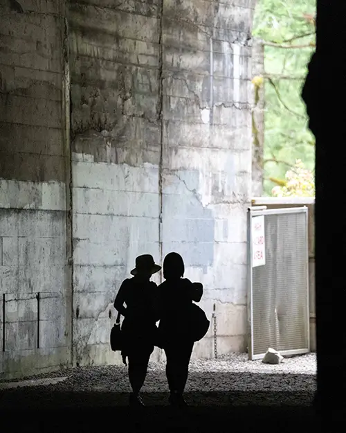 Silhouette of two people walking out of a tunnel