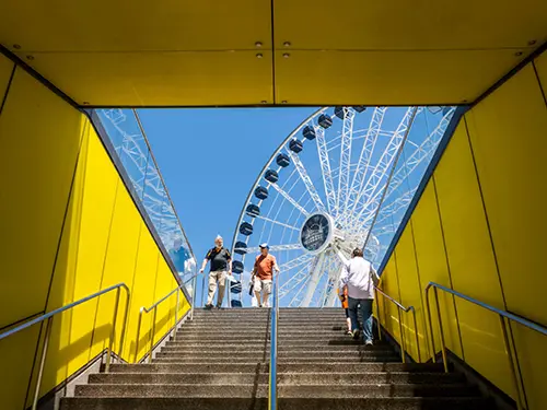 People walk on stairs with a ferris wheel in the background