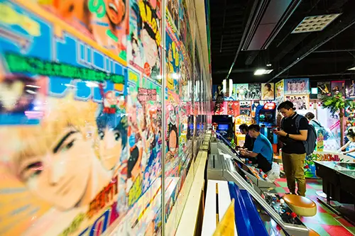 People play at an arcade in Tokyo, with covers of Manga on the walls