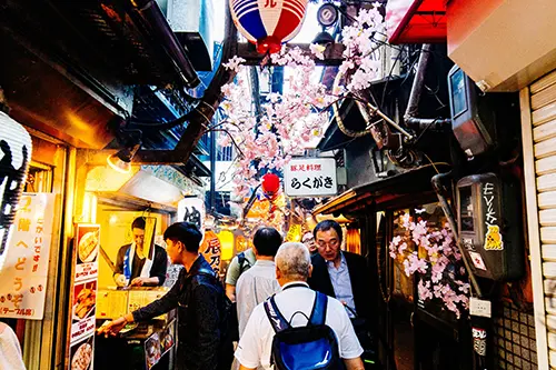 People walking through a narrow food alleyway in Tokyo