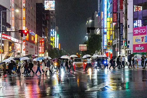 Crowd of people with umbrellas cross the street in Tokyo rain