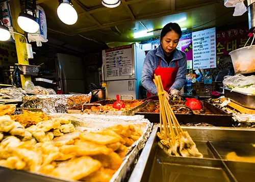 Person prepares Korean food at a street food stall